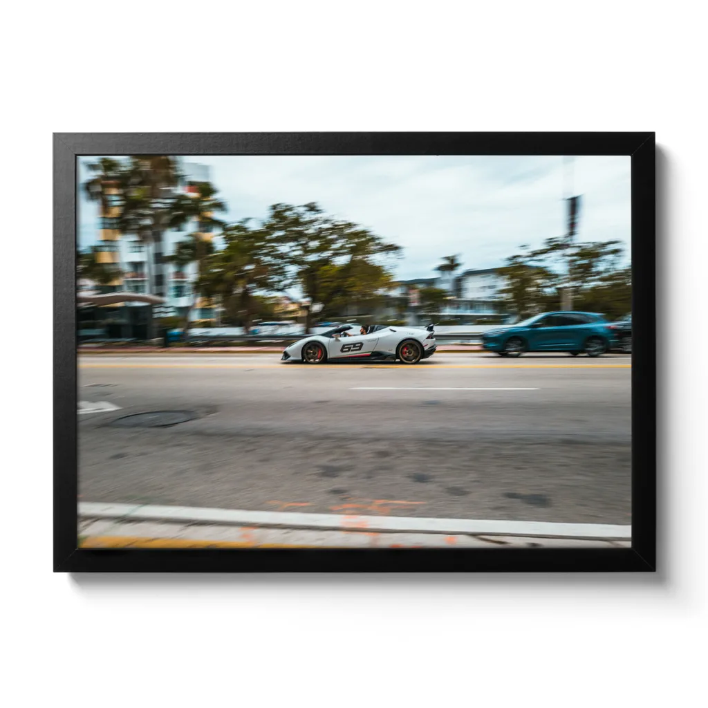 Bildaufnahme eines schnellen weißen Lamborghini der durch Miami flitzt. Aufschrift 69.