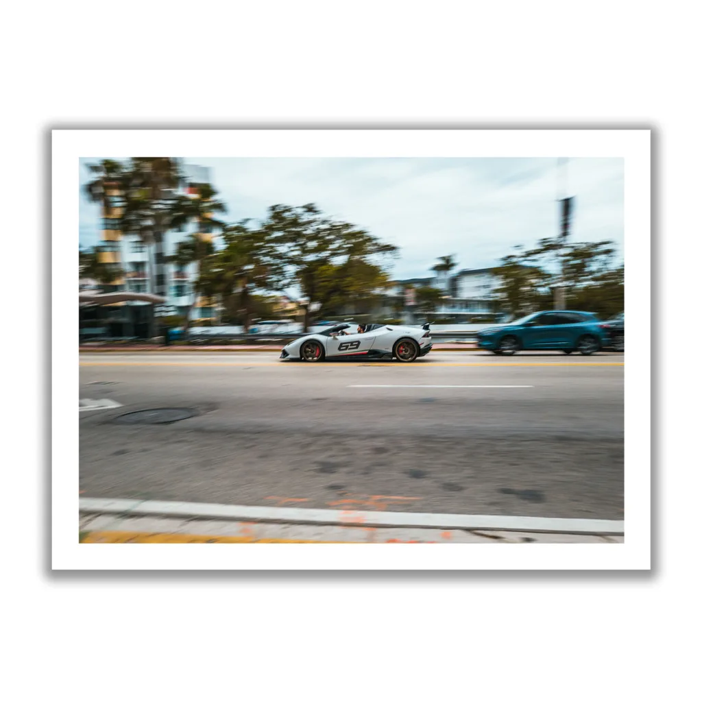 Bildaufnahme eines schnellen weißen Lamborghini der durch Miami flitzt. Aufschrift 69.